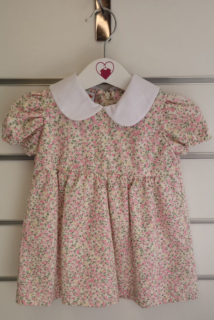 Floral dress hanging on a door handle with a heart-shaped tag.