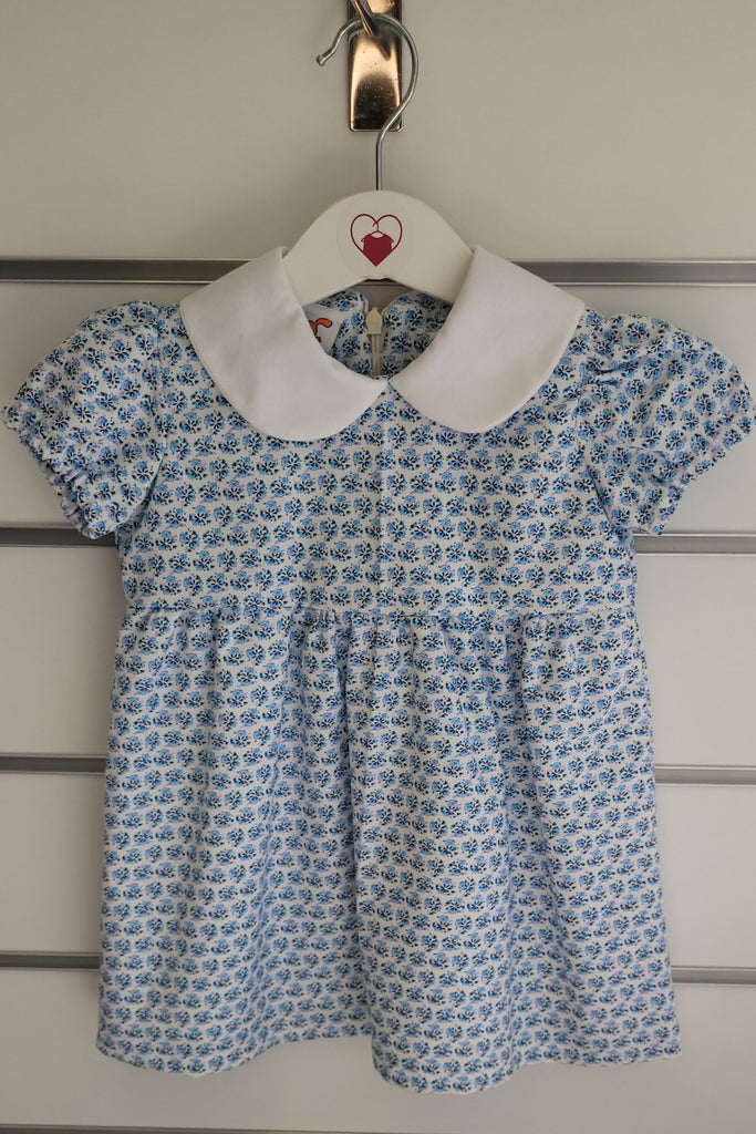 Blue patterned dress on a hanger against a neutral wall